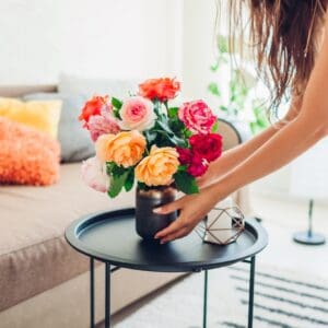 Woman arranging colorful flowers on table.