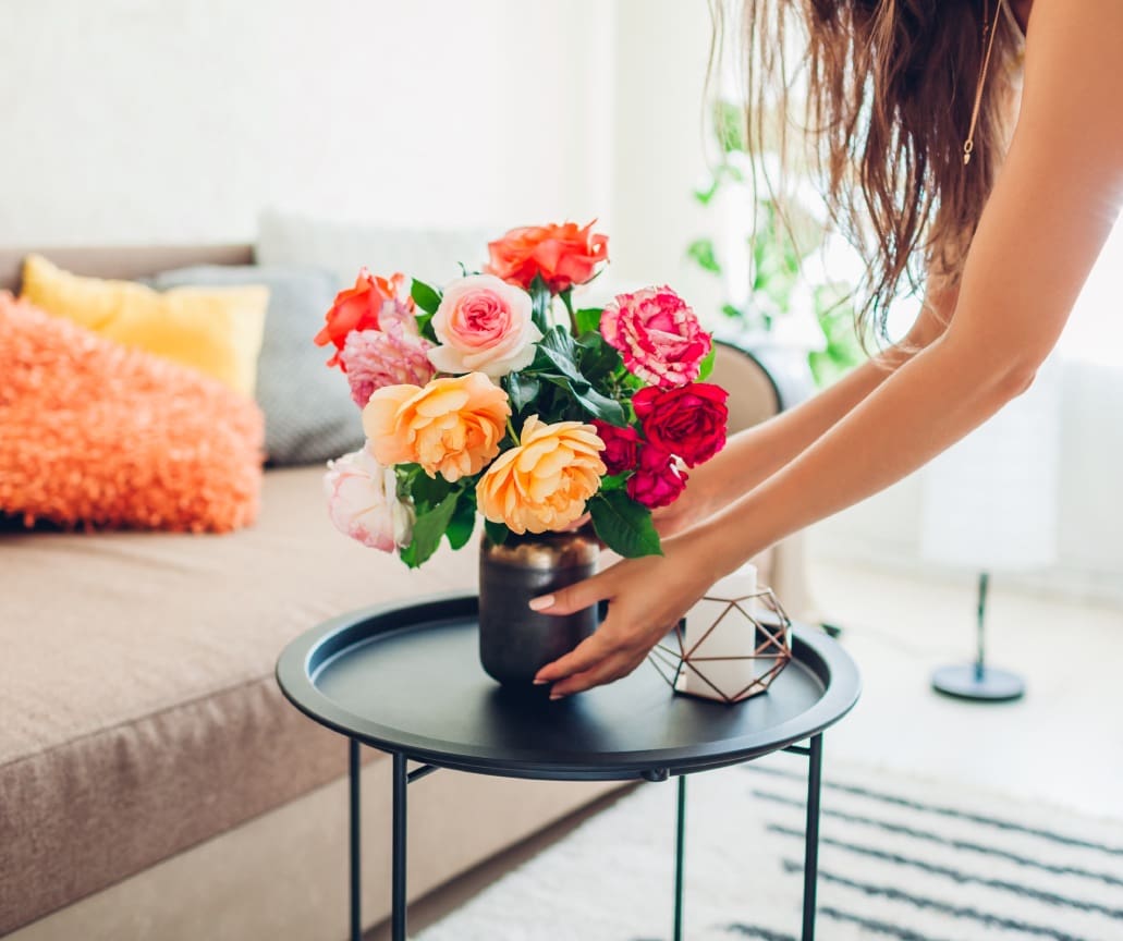 Woman arranging colorful flowers on table.