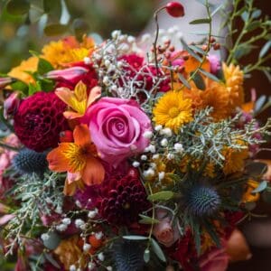 Colorful bouquet with pink rose and greenery.